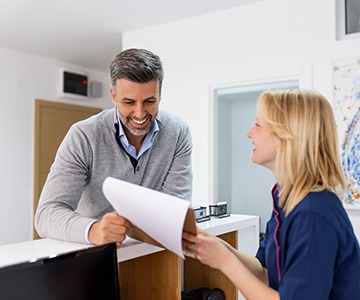 a man speaking to a front desk receptionist about insurance coverage