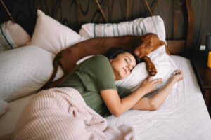 Woman sleeping in her bed with a dog